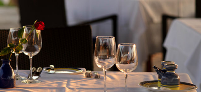 table for romantic dinner with wine glasses and red roses in Kalimera Kriti Hotel's restaurant