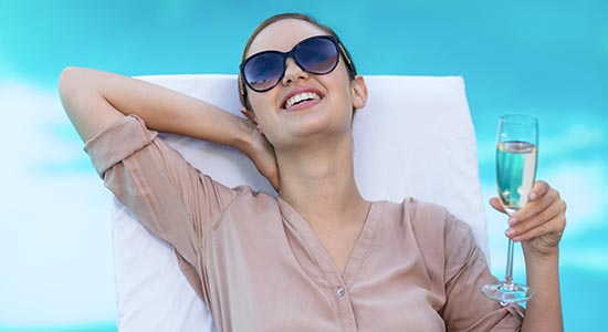 woman relaxes on sunbed with a glass of wine in Kalimera Kriti Hotel terrace